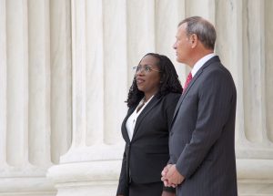 ketanji brown jackson and john roberts stand next to each other in front of large marble column