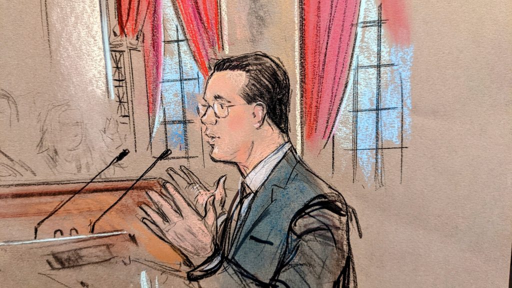 sketch of man with glasses gesturing before the podium.