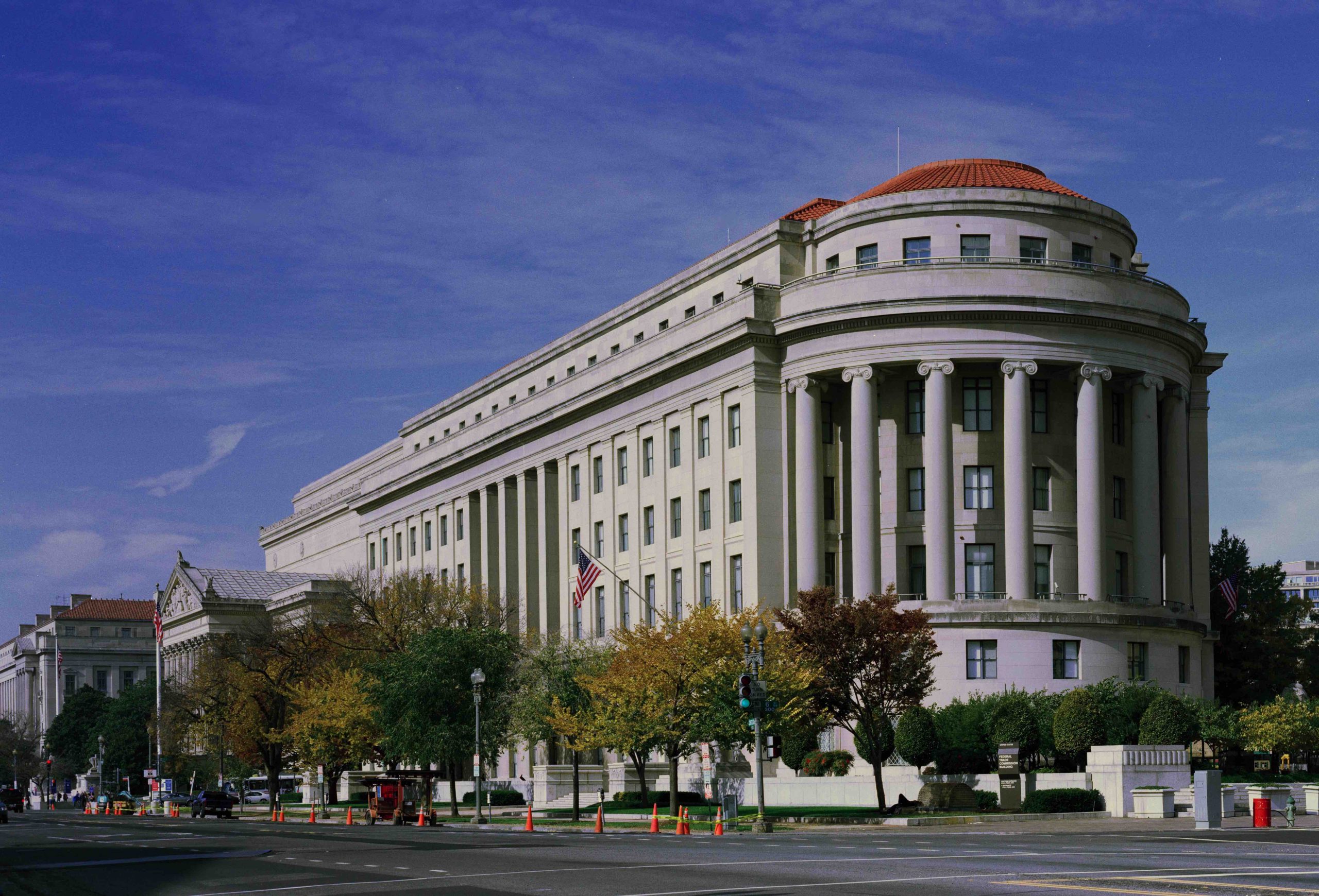 limestone building in the classical revival architectural style. a semi-circular portico, fronted by pillars, faces the street.