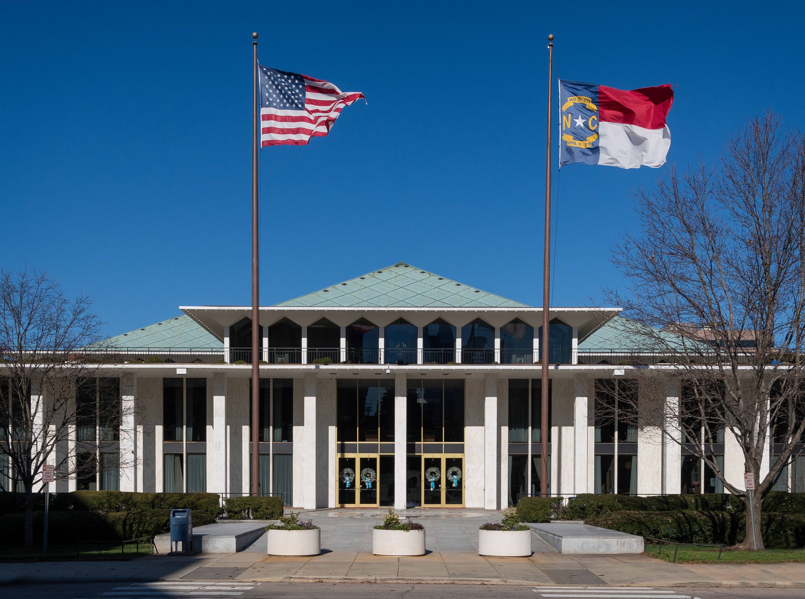 US and North Carolina flags flying in front of the North Carolina legislative building