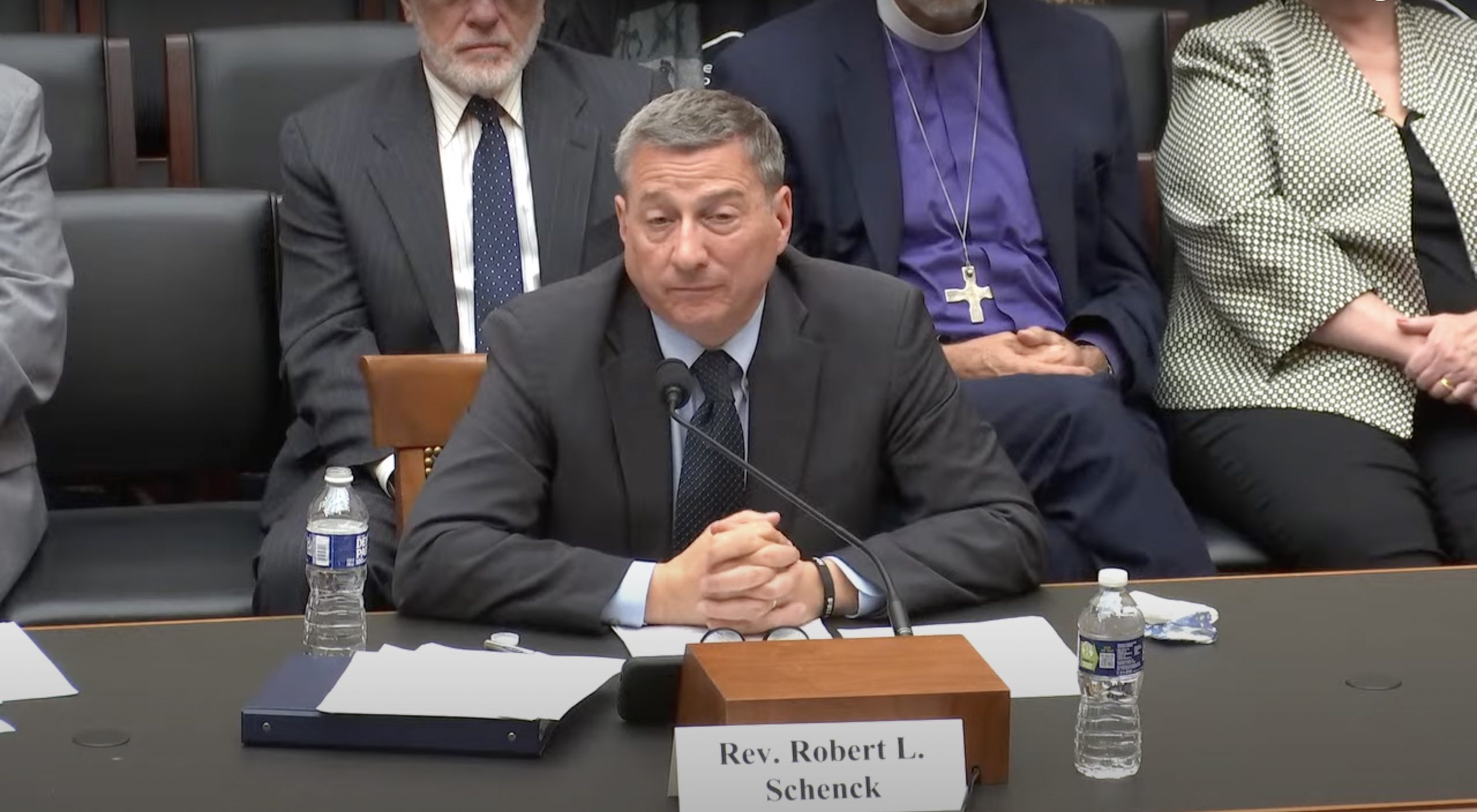 Man speaking into microphone at desk.