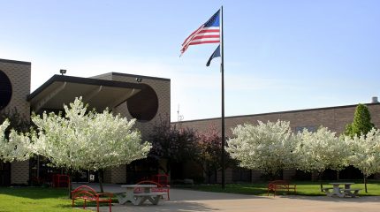 school building american flag and flowering trees on front lawn