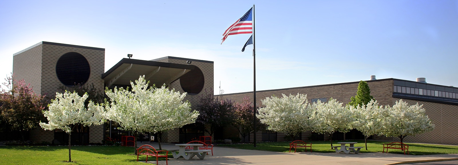 school building american flag and flowering trees on front lawn