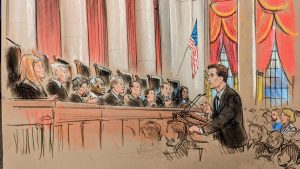 A man at a podium talks to nine justices on the bench.