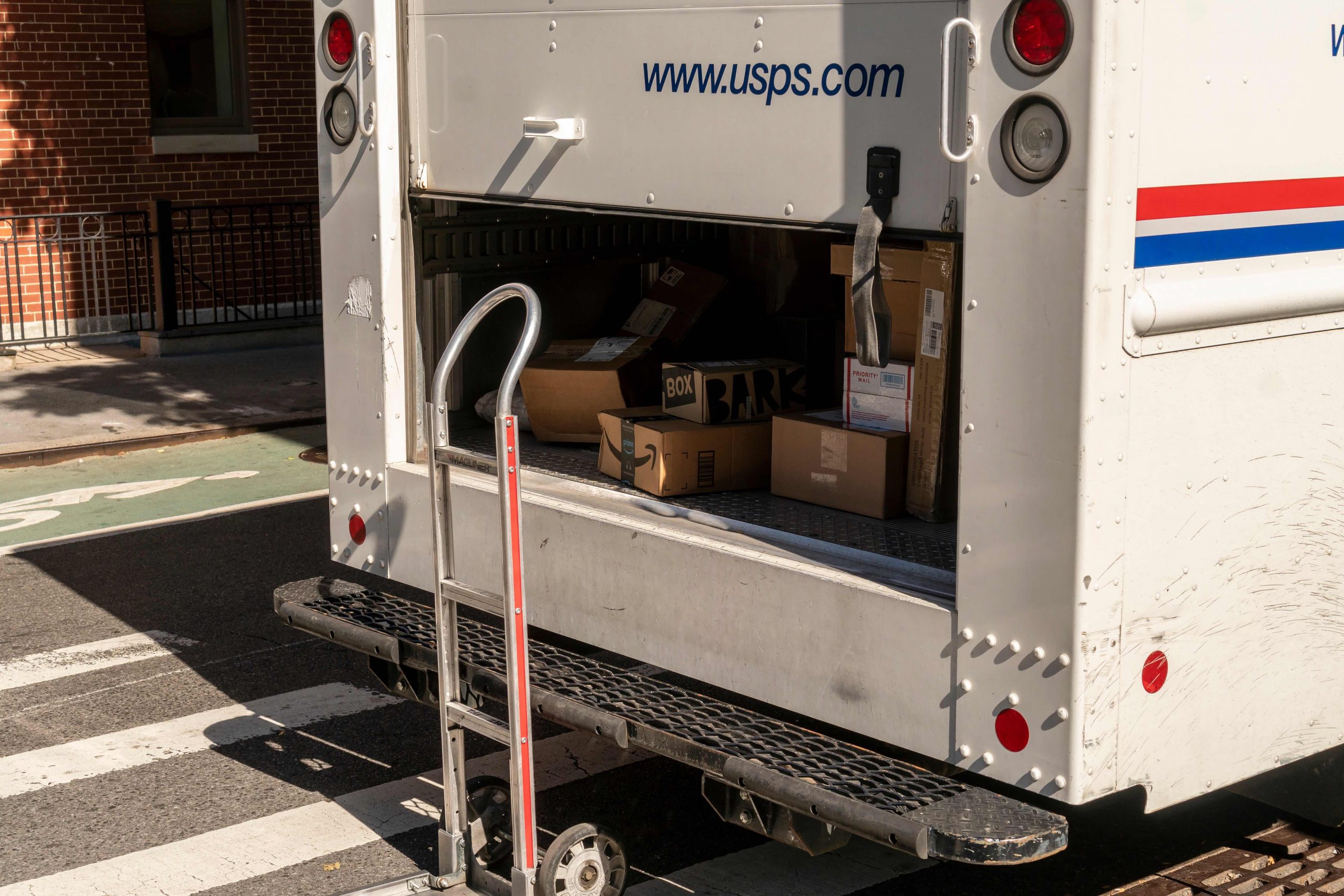 The back of a mail truck with packages stacked inside.