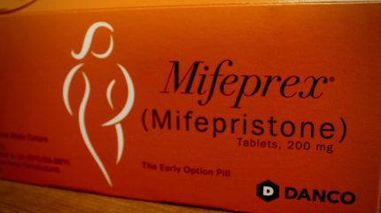 Orange box with "Mifeprex (mifepristone)" and a figure of a woman on it.