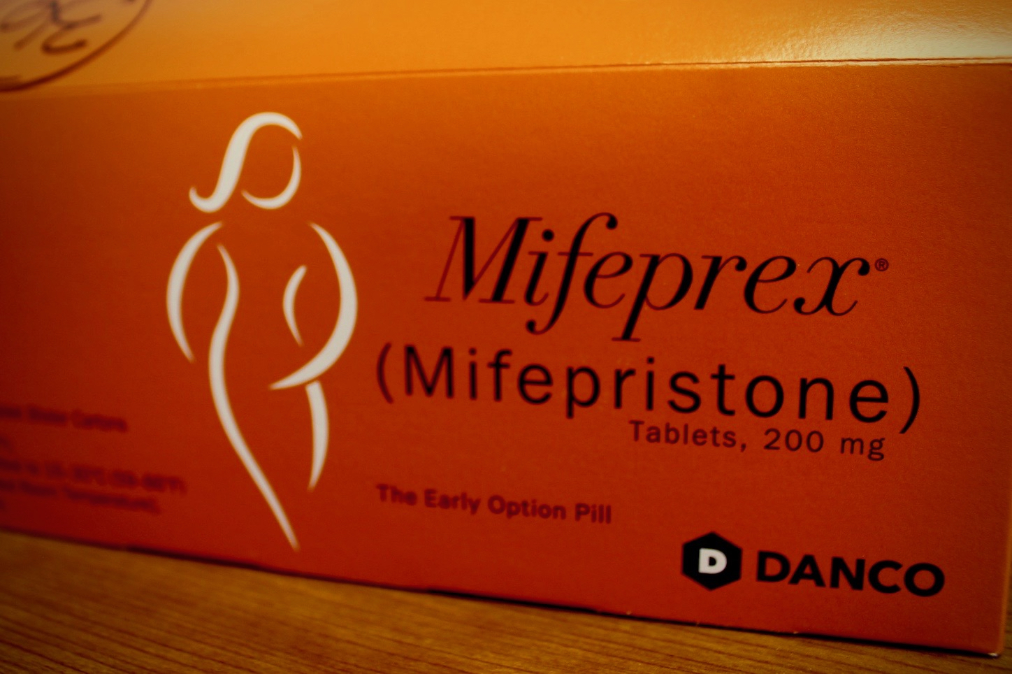 Orange box with "Mifeprex (mifepristone)" and a figure of a woman on it.