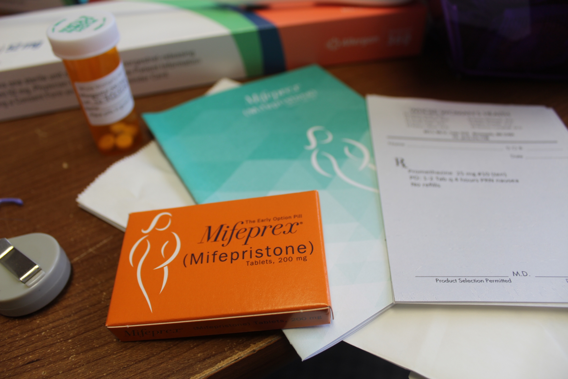 Una mesa con folletos médicos y una caja de la píldora abortiva mifepristona