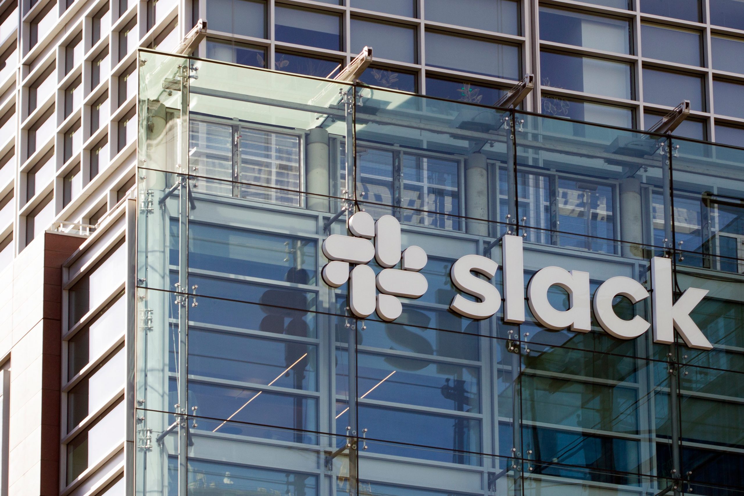 The facing of a glass office building with the company logo for Slack on the outside.