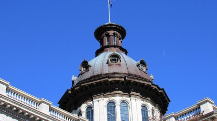 Dome of the South Carolina State House building with flags flying.