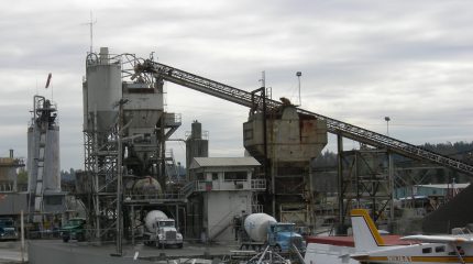 A cement plant with trucks being loaded with cement.