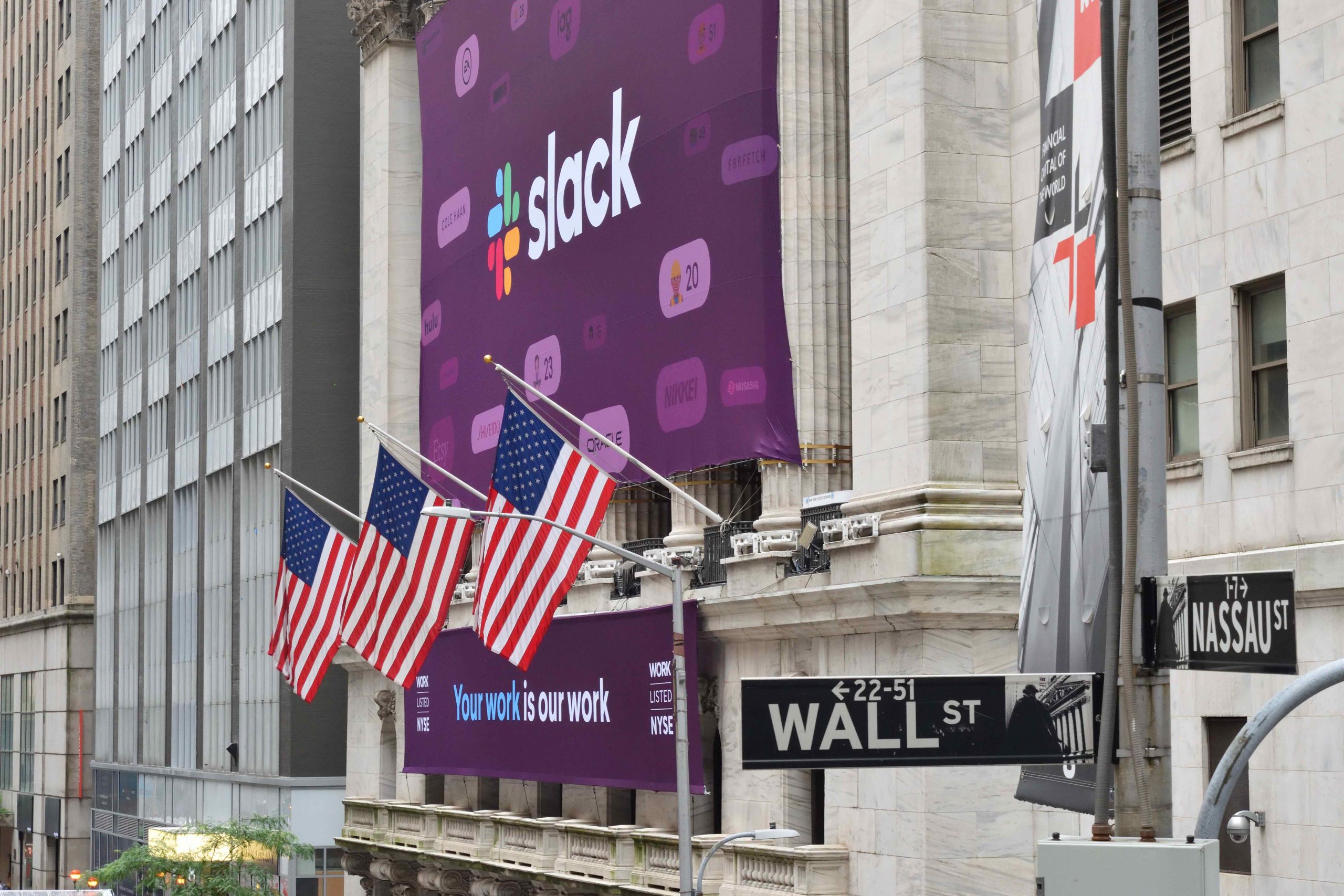 Una gran pancarta con el logotipo de la empresa Slack cuelga de un edificio de mármol con banderas estadounidenses en el frente.