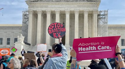 A crowd holding protest signs outside the Supreme Court, for and against abortion.