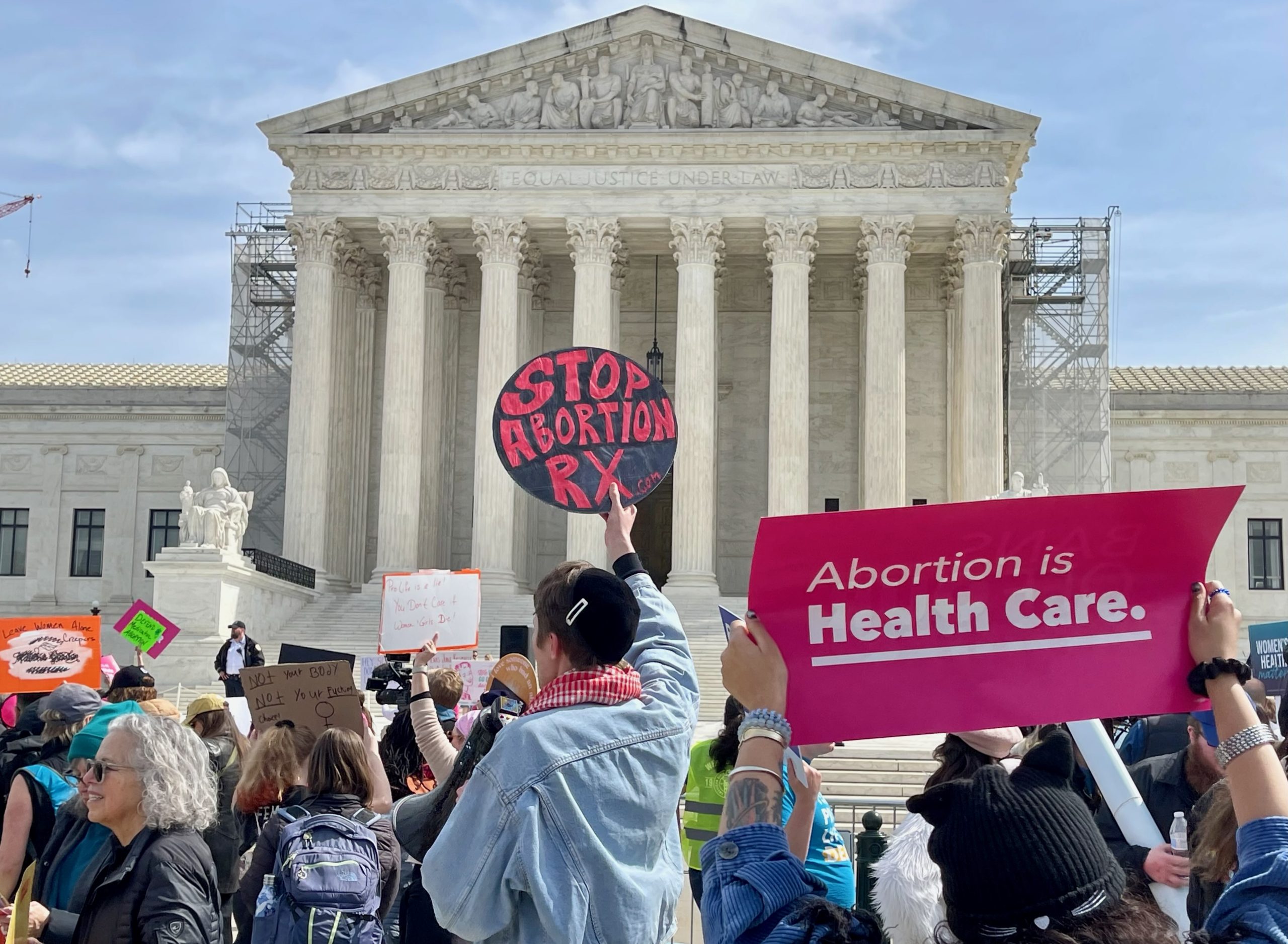 A crowd holding protest signs outside the Supreme Court, for and against abortion.