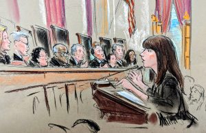 Woman speaking at a lectern to a bench of justices 